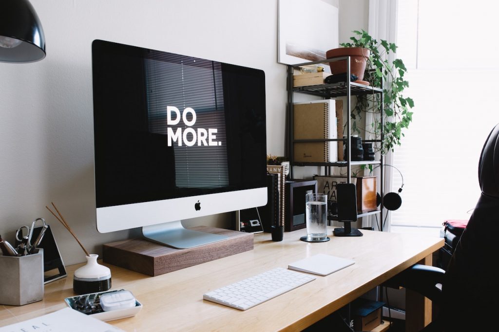 Un bureau avec un ordinateur avec un écran noir et écrit en blanc en grosse lettre : "Do more"