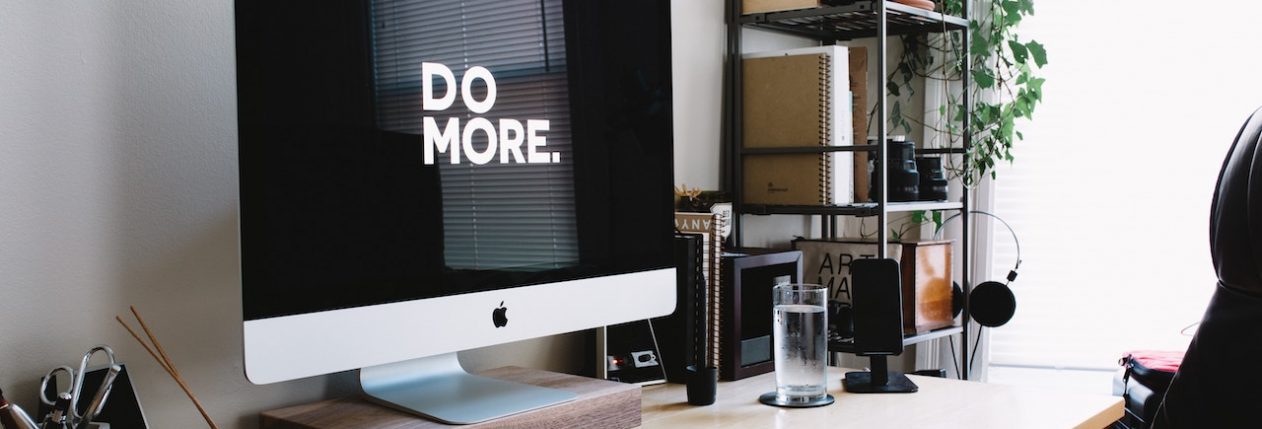 Un bureau avec un ordinateur avec un écran noir et écrit en blanc en grosse lettre : "Do more"