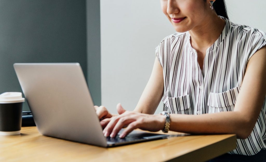 Femme assise à une table devant son ordinateur en souriant