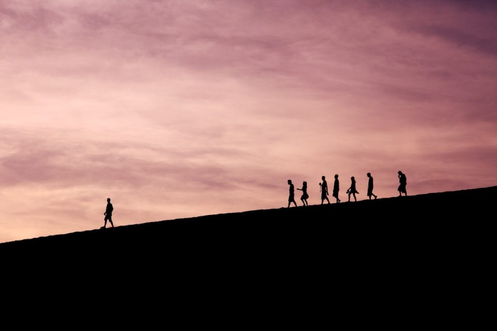 Un groupe d'individu suit une personne sur une colline.