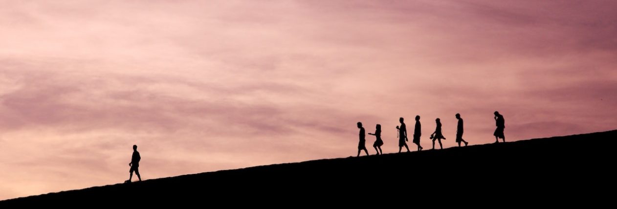Un groupe d'individu suit une personne sur une colline.