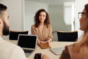 Un entretien d'embauche : une femme est assise en face de deux autres individus à une table.