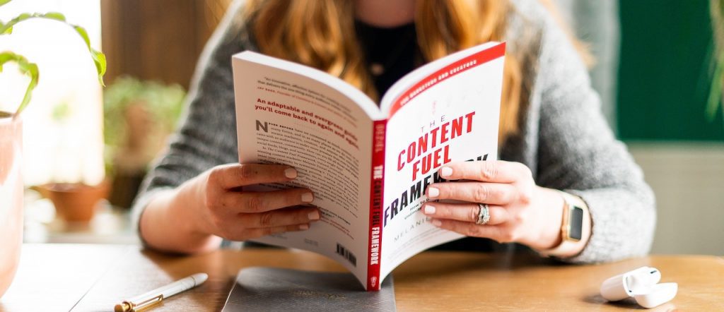 Une femme assises à une table lit un livre de formation.