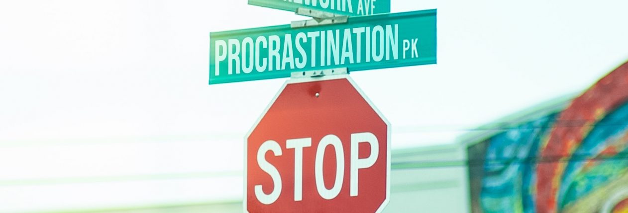 Un panneau STOP au-dessus duquel il y a deux petits panneaux verts avec écrit "homework" et "procrastination".