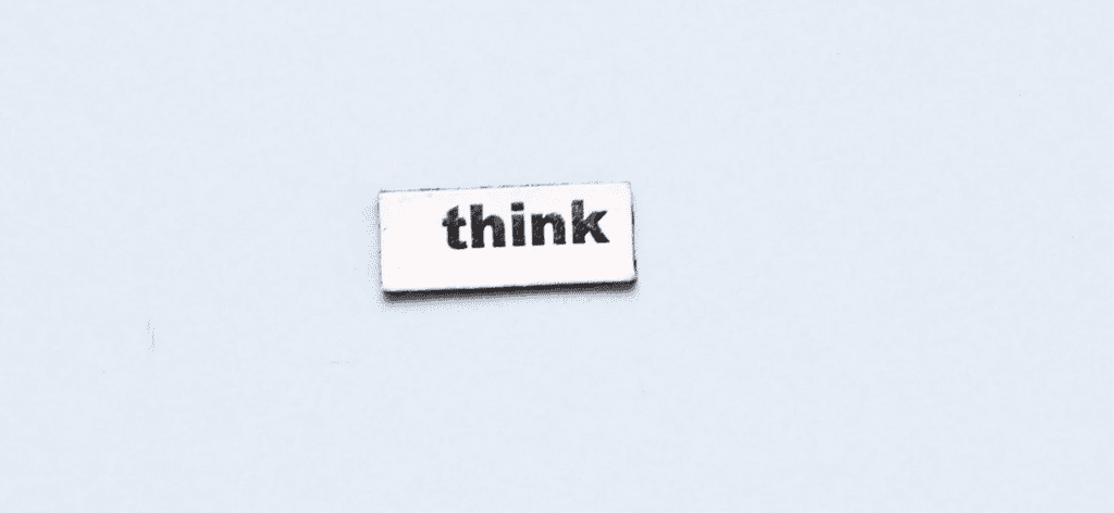 Le mot "Think" écrit sur un morceau de papier blanc sur un fond neutre bleu clair.