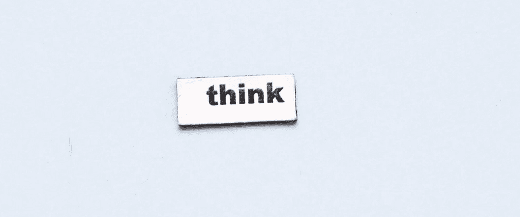 Le mot "Think" écrit sur un morceau de papier blanc sur un fond neutre bleu clair.