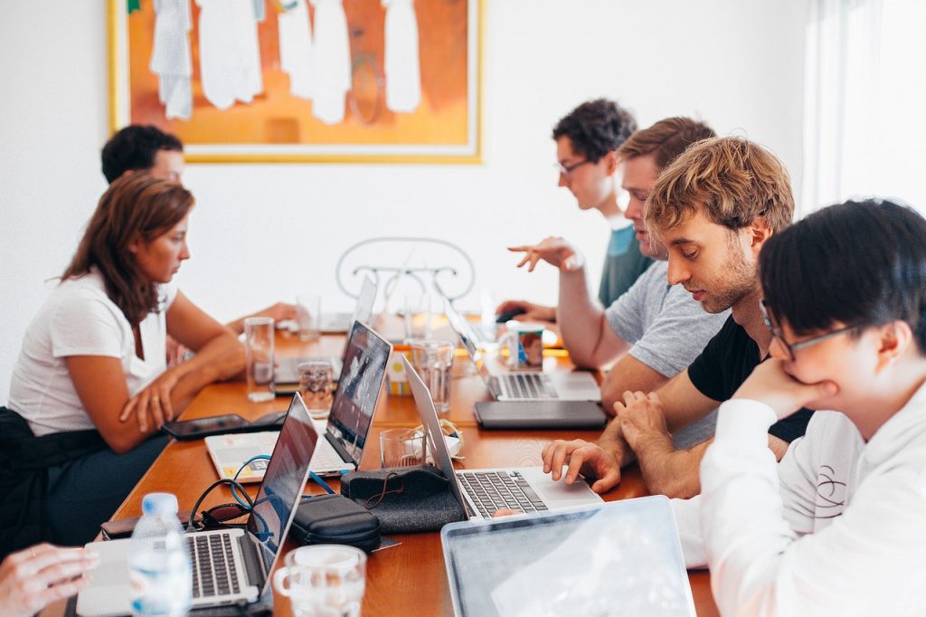 Une équipe de personnes assises autour d'une table avec leurs ordinateurs portables.