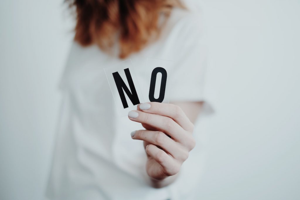 Une femme tient deux lettres dans sa main et les montre à la caméra : N et O, pour Non.