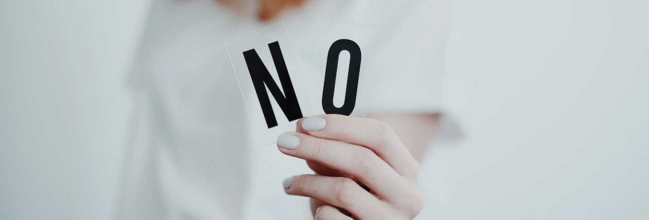 Une femme tient deux lettres dans sa main et les montre à la caméra : N et O, pour Non.