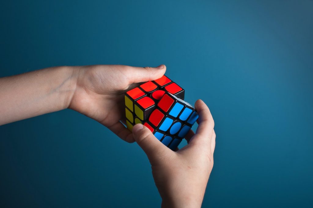 Des mains en train de résoudre un Rubik's Cube sur un fond bleu.