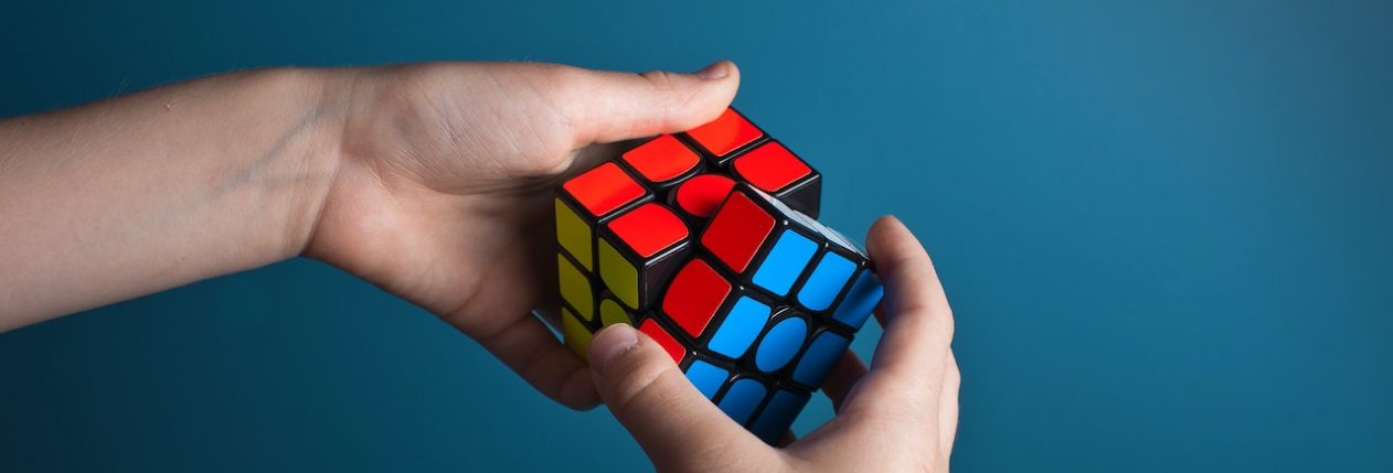 Des mains en train de résoudre un Rubik's Cube sur un fond bleu.