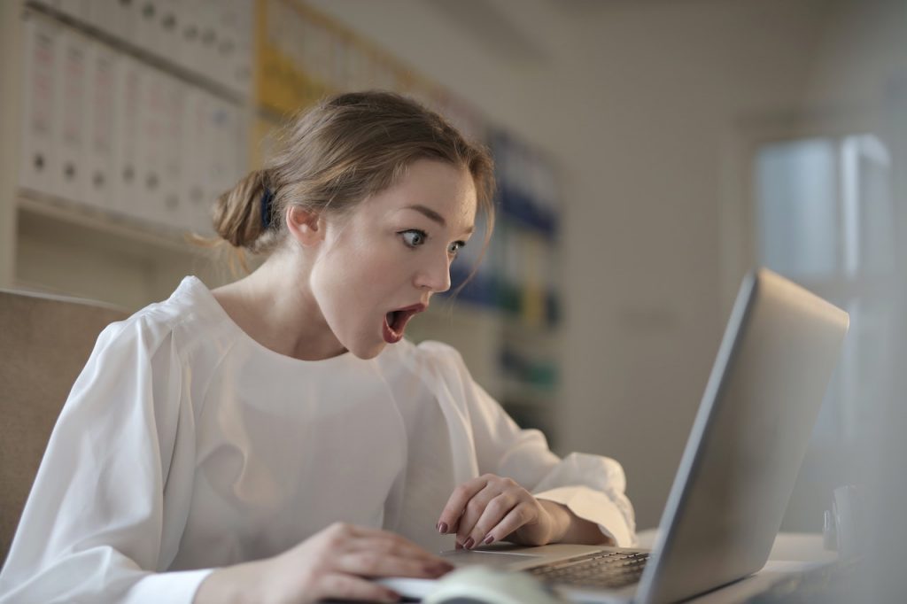 Une femme à son bureau devant son écran à l'air très surprise parce qu'elle voit.