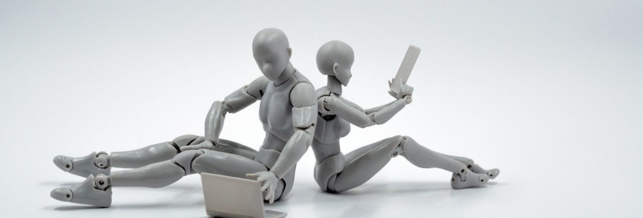 Deux humanoîdes, dos à dos, sur des ordinateurs portables.
