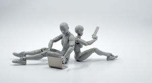 Deux humanoîdes, dos à dos, sur des ordinateurs portables.