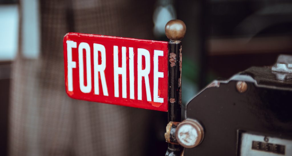 Un panneau rouge avec écrit "For Hire" qui signifie "disponible à l'emploi" en anglais.