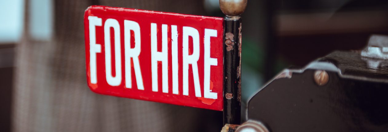 Un panneau rouge avec écrit "For Hire" qui signifie "disponible à l'emploi" en anglais.