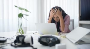 Une femme assise à son bureau, la tête dans les mains.
