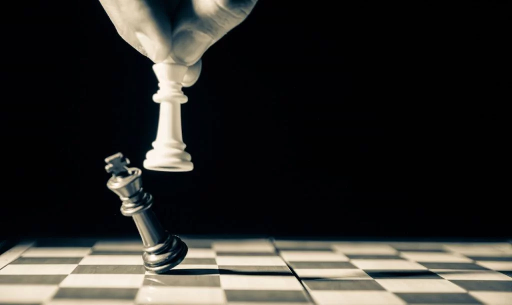 Un jeu d'échec : une personne pousse un pion pour placer le sien.