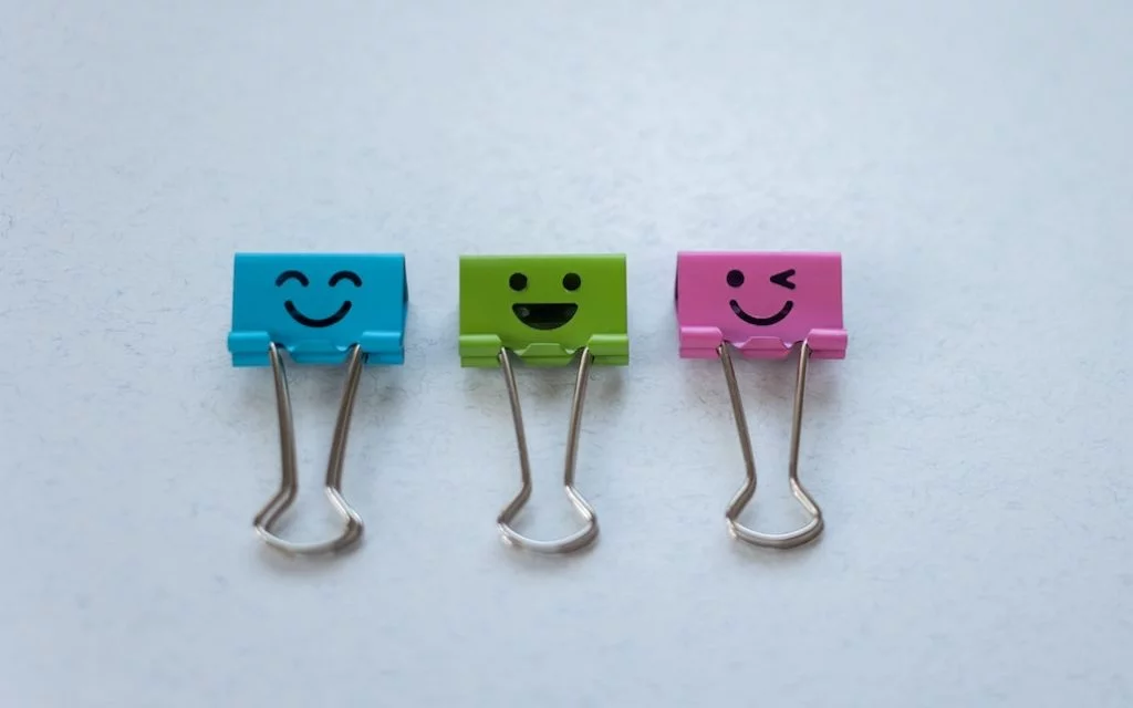 Des trombones de différentes couleurs sur lequelles on a dessiné des smileys.