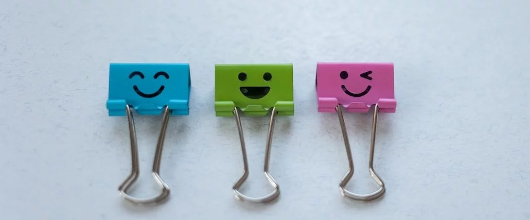 Des trombones de différentes couleurs sur lequelles on a dessiné des smileys.